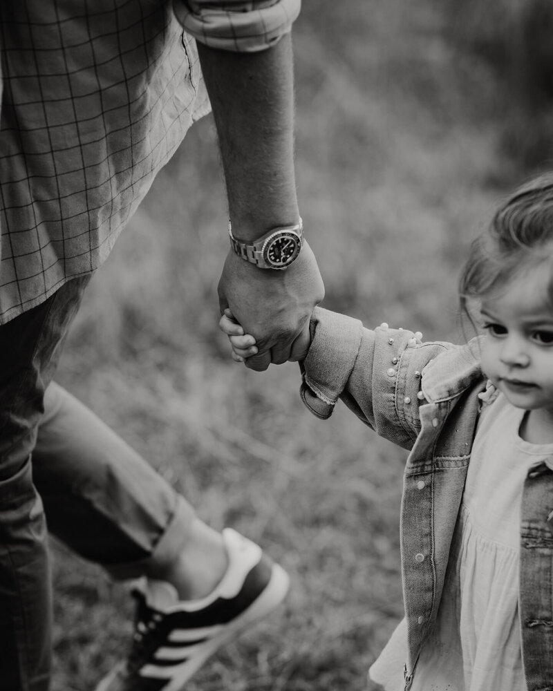 Close up of toddler holding her daddy's hand