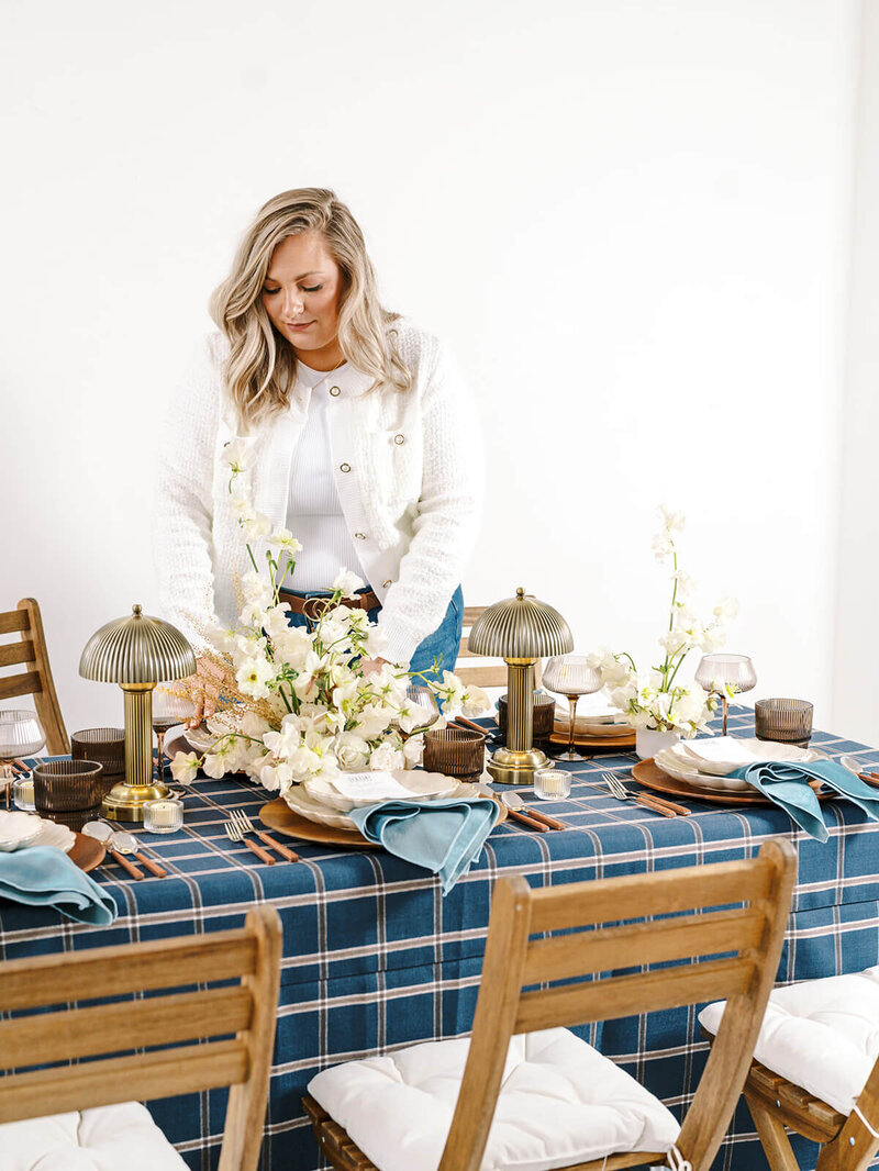 A wedding planner sets a table at a styled photoshoot for her brand.