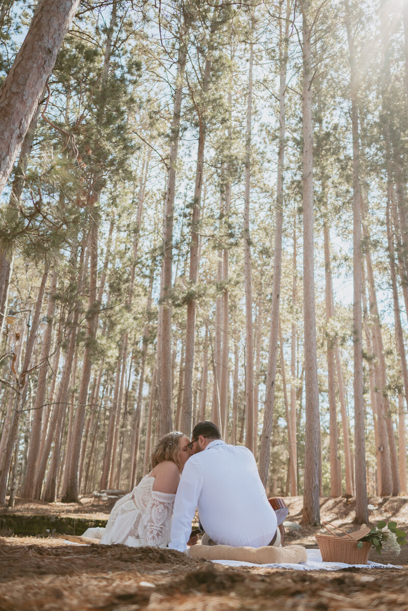 a married couple kissing middle of forest