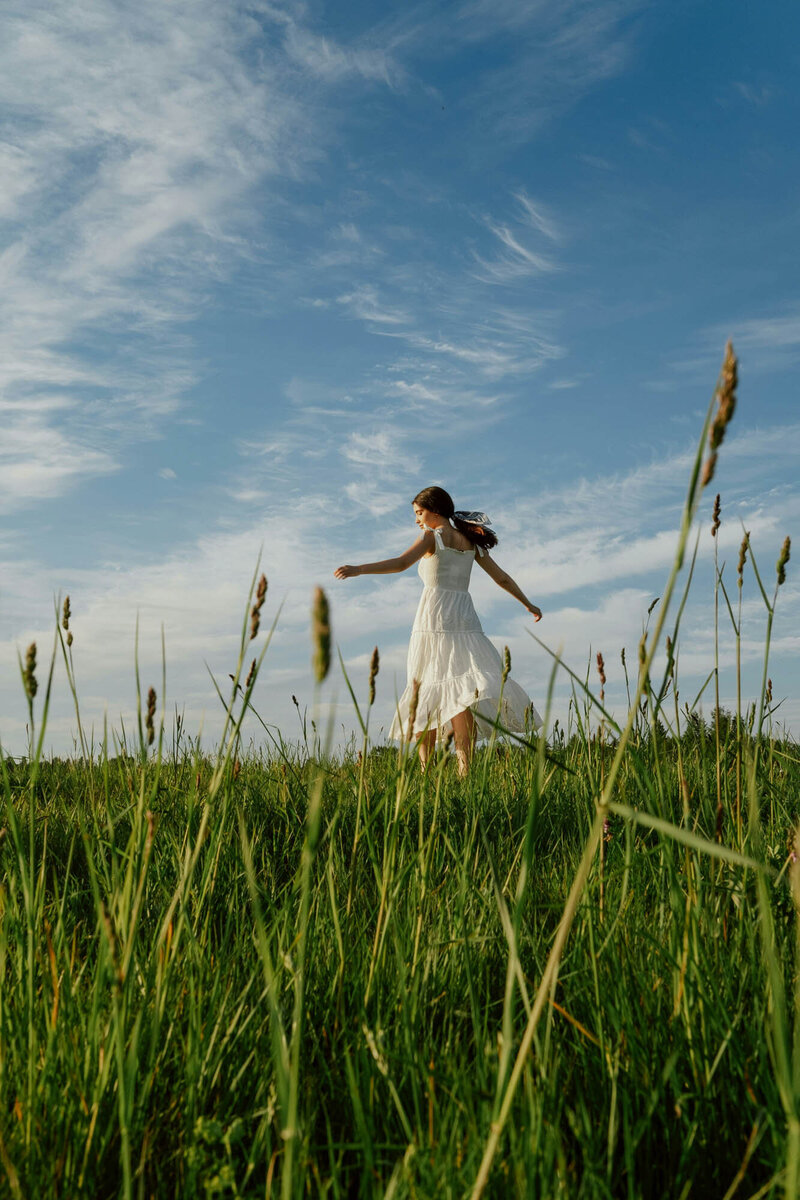 Woman in white dress frolicking in green field