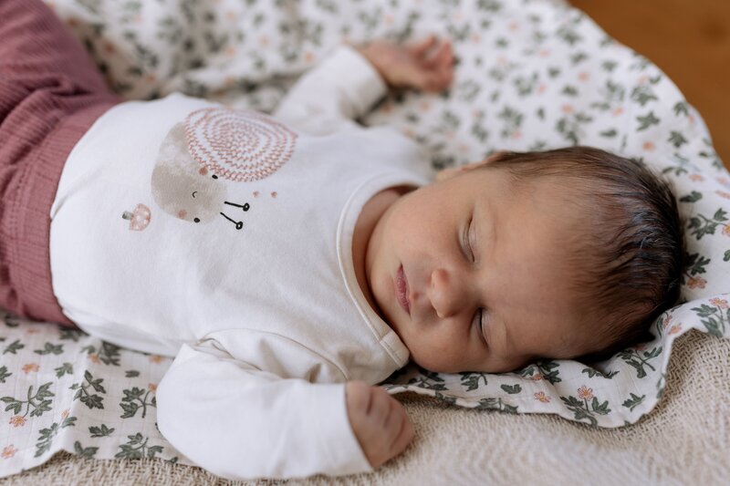 Schlafendes Baby auf Blumenmuster Decke
