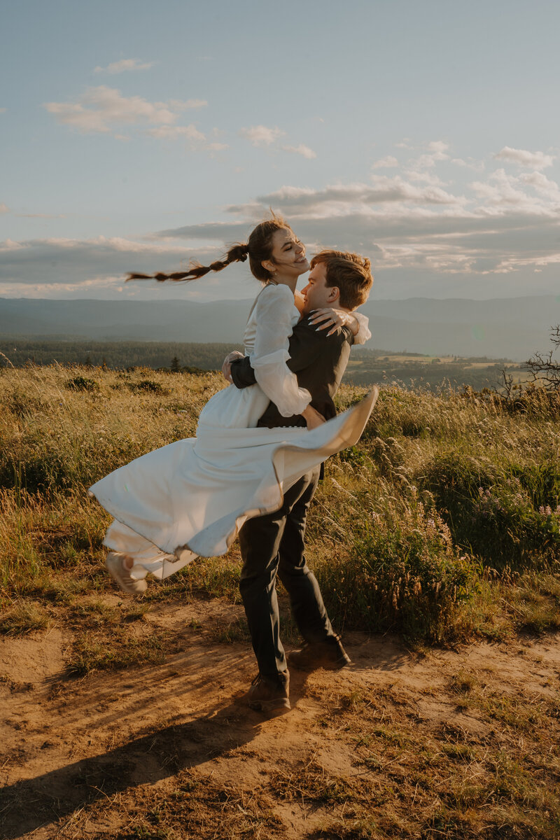 groom spinning bride around on a mountain top