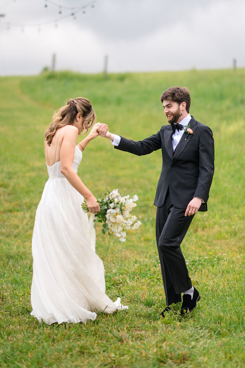 A bride and groom dancing in a field.