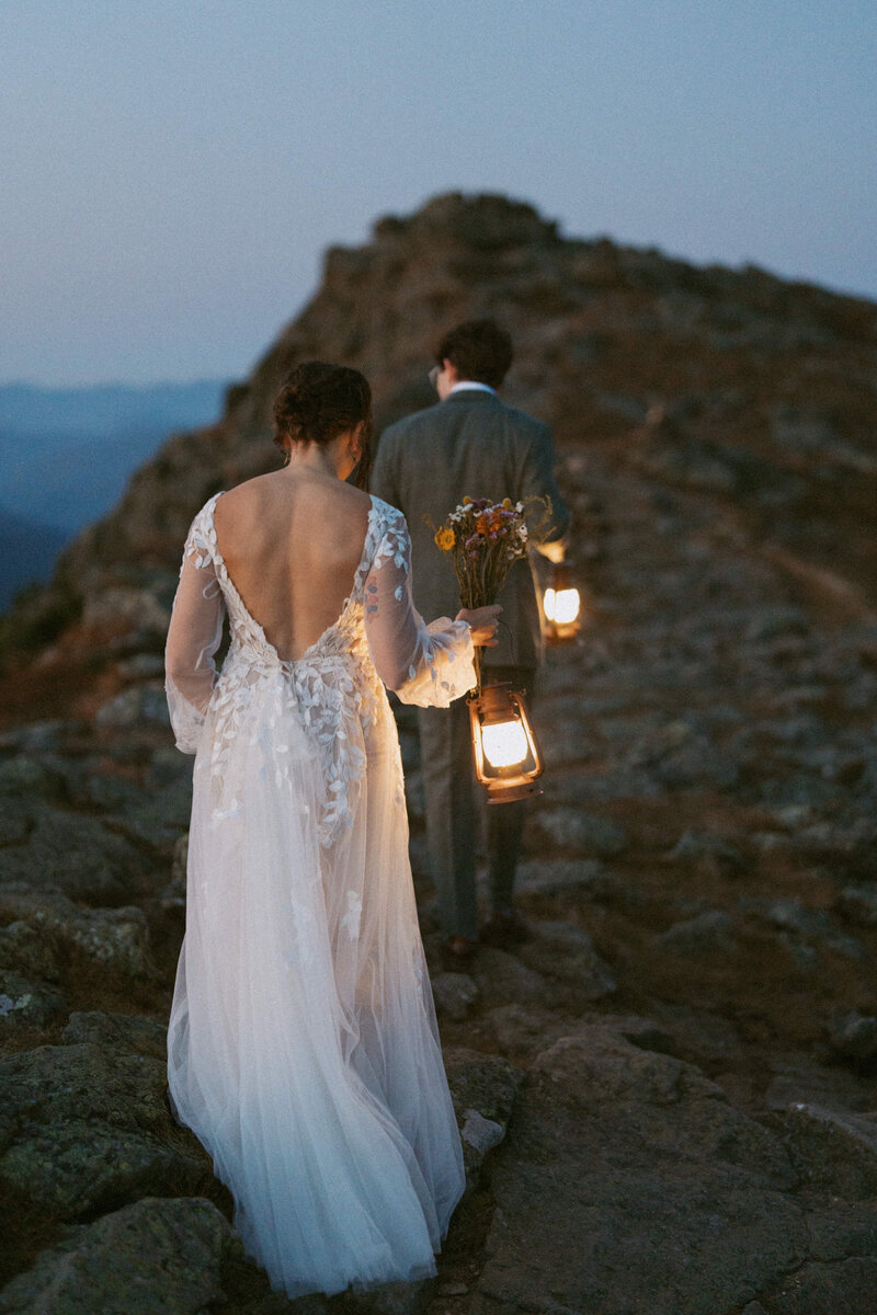 Bride and groom carrying lanterns up to the summit of Mount Monroe during their elopement in the White Mountains, New Hampshire.