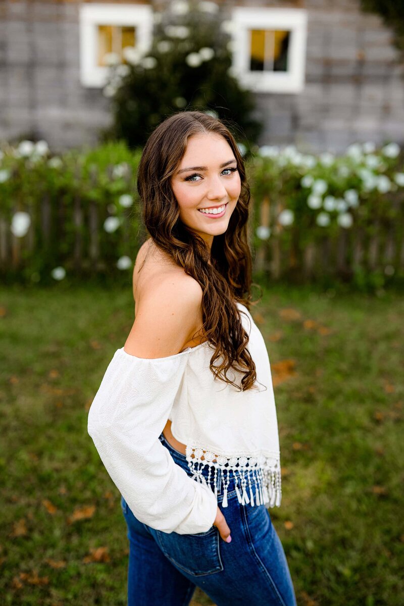 senior girl has hand in pocket of jeans looking back over her shoulder during her grad session