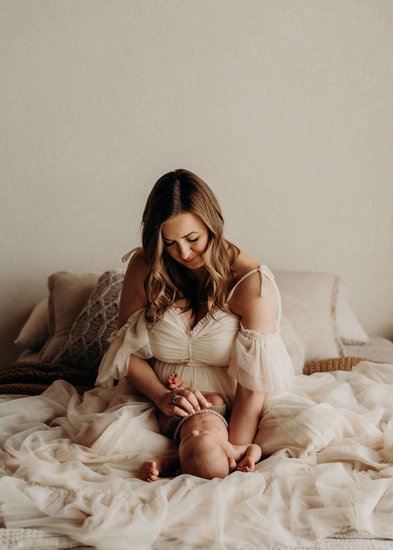 mother in gorgeous dress posing with her newborn at a newborn photo session in denver colorado