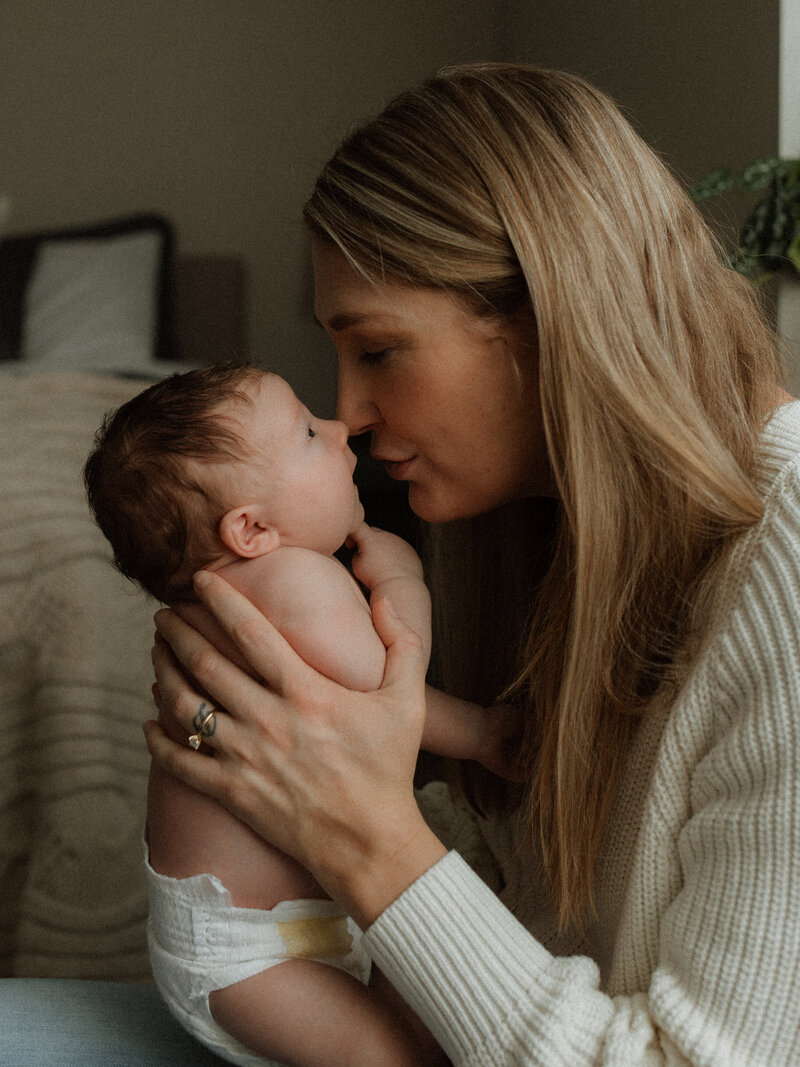 Mother holding her newborn baby close during an in-home lifestyle photography session in Canyon Lake, CA.