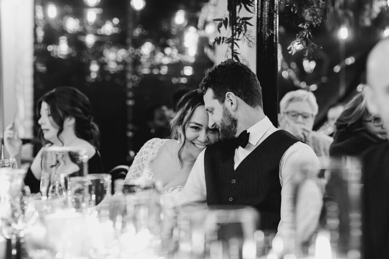 Candid of Bride and groom sitting at dinner having a quite moment of interaction in marquee in winter