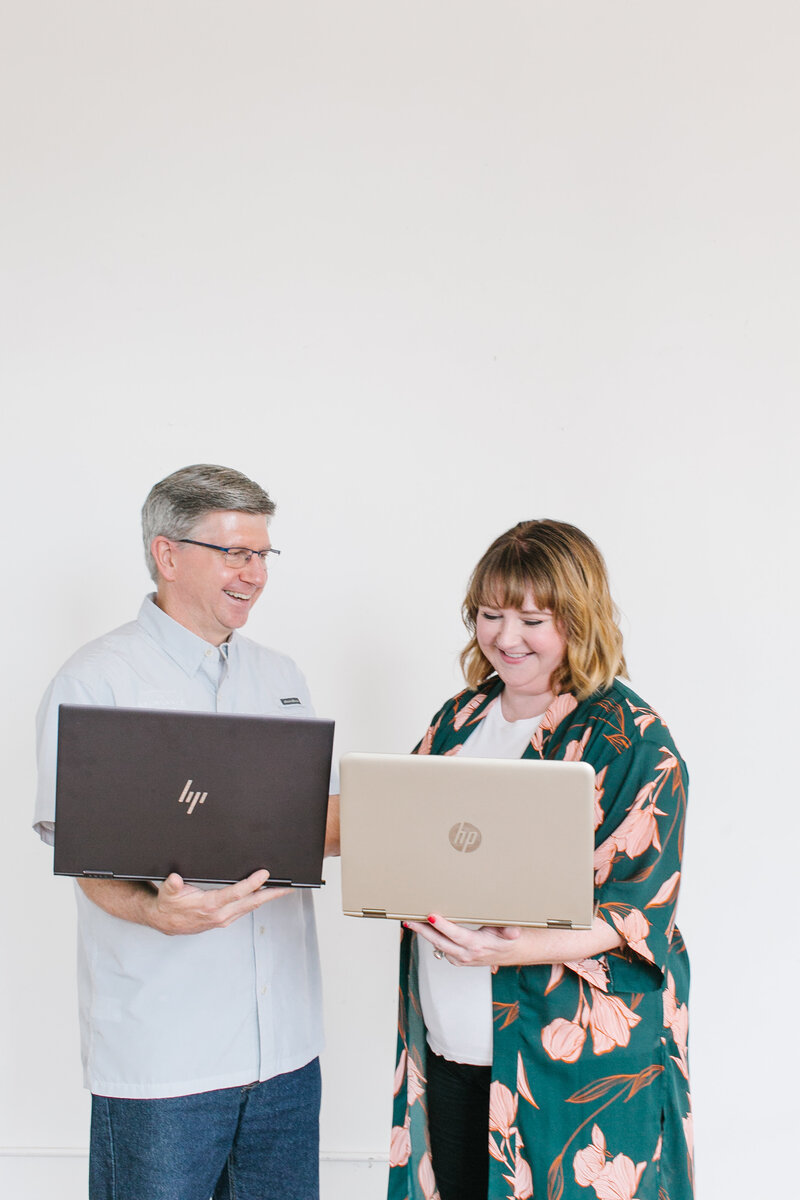 Founders of The Abundance Group, smile and work on their laptops together