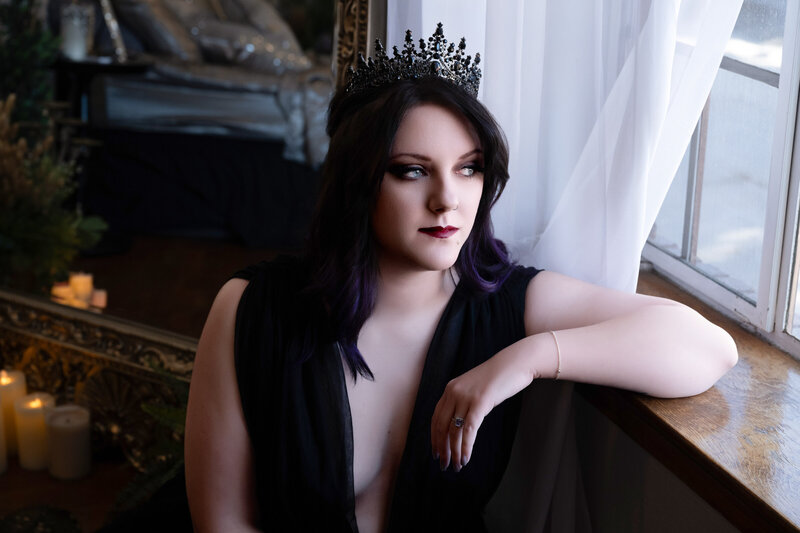 Boudoir portrait of woman with blush wings in a studio setting, tattoos on arm