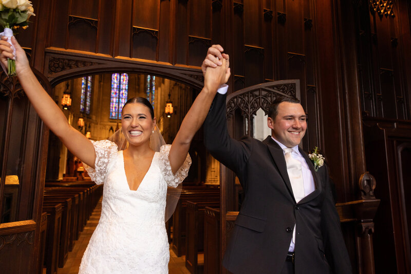 Bride and groom hold hands as they are welcomed by family and friends as they exit Heinz Chapel on their wedding day. Photographed by Aaron Aldhizer