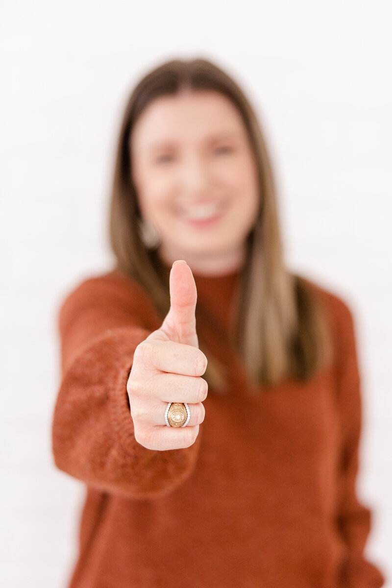 Girl smiling in sweater with thumbs up and Aggie Ring with ring wrap