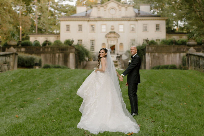 Below the waste close up of bride and groom holding hands and bouquet