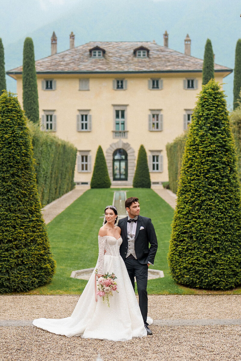 bride and groom standing in front of large estate
