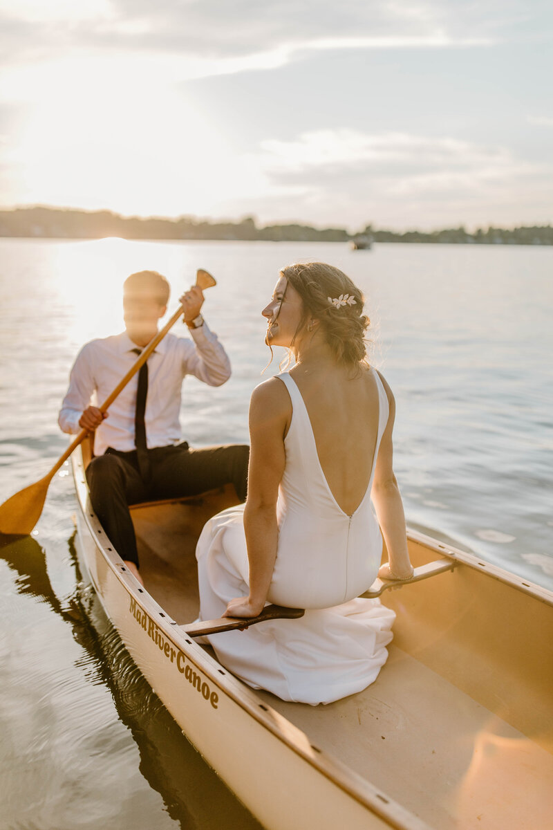 bride and groom in canoe  on lake at sunset