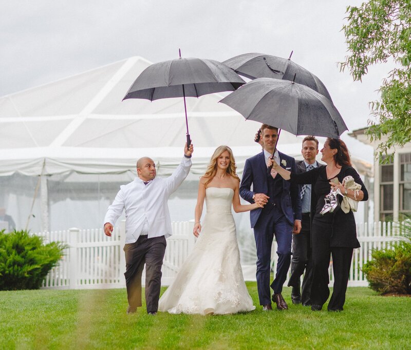 Leslie Price holding umbrella for bride and groom