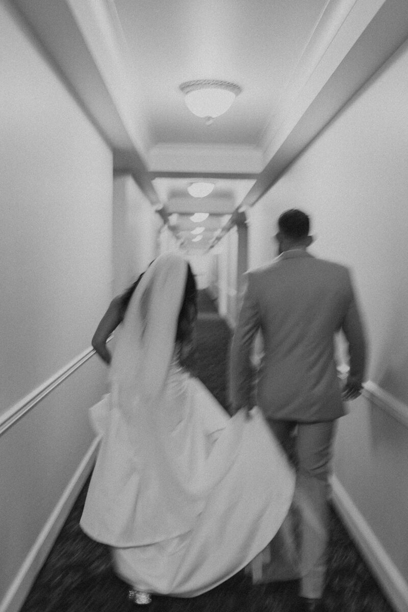 bride and groom running down hallway