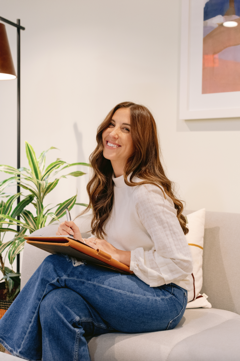 female therapist with curly brown hair sitting with notepad