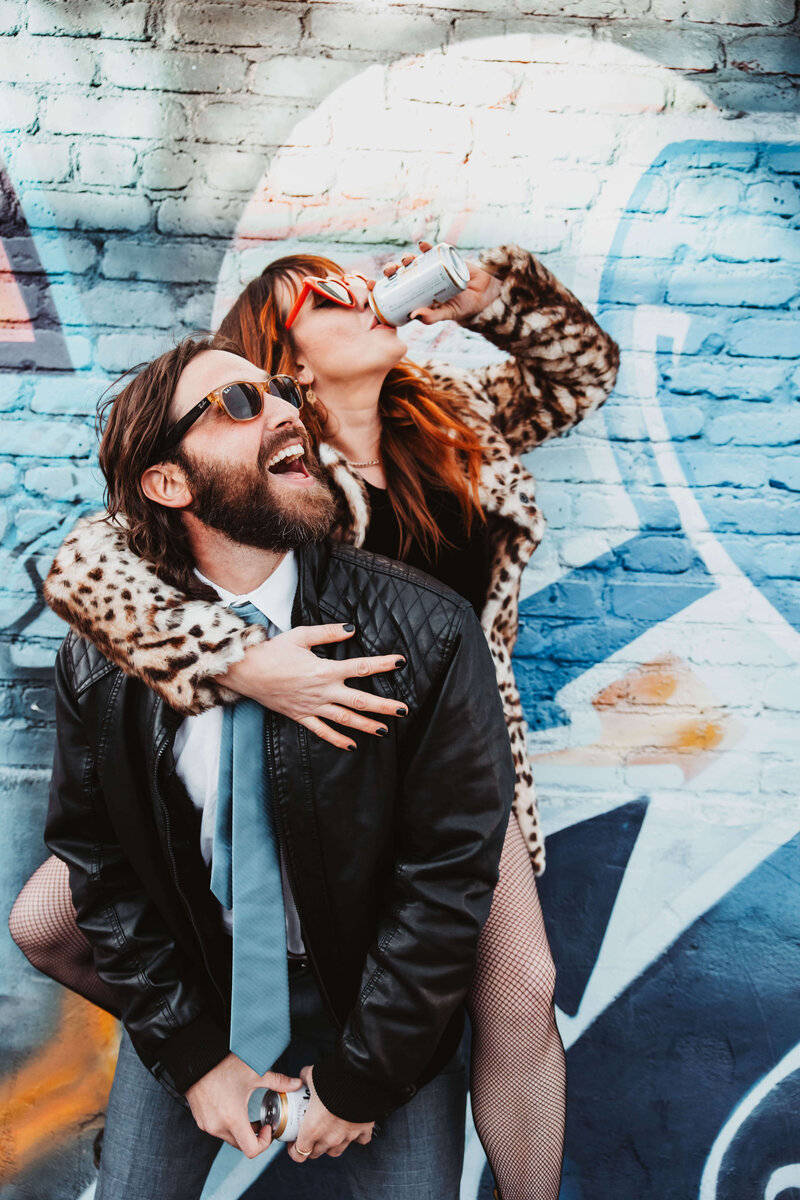 Man Giving Woman Piggyback Against Graffiti Wall