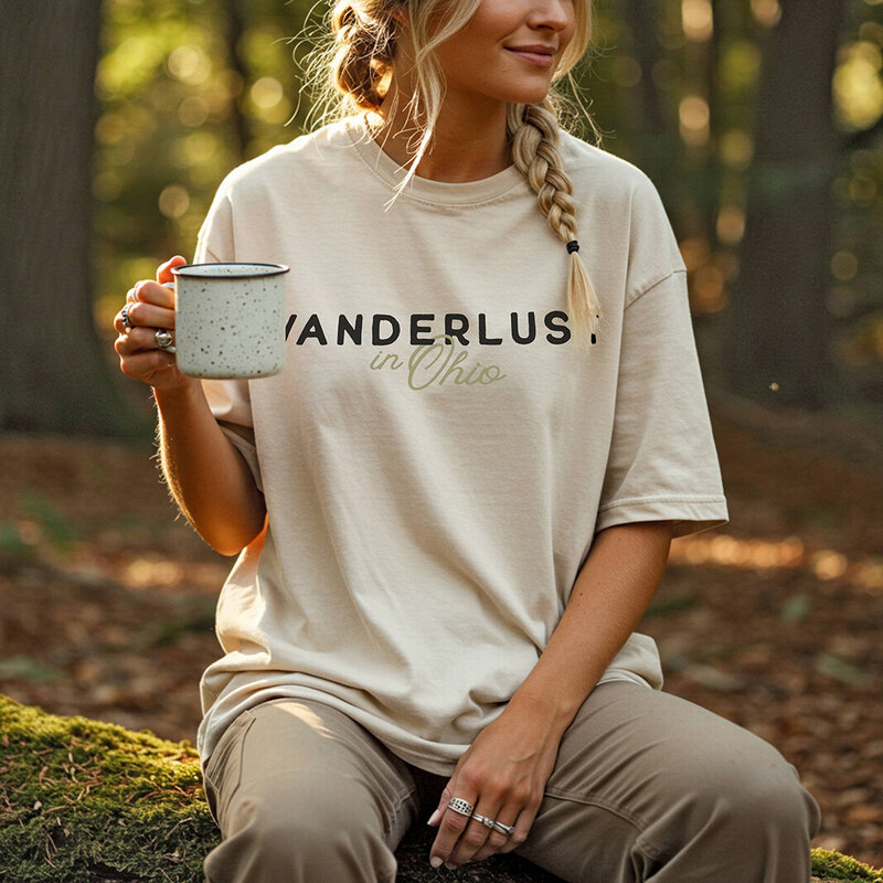 A woman in a t-shirt featuring the word "Wanderlust" representing her travel blogger brand.