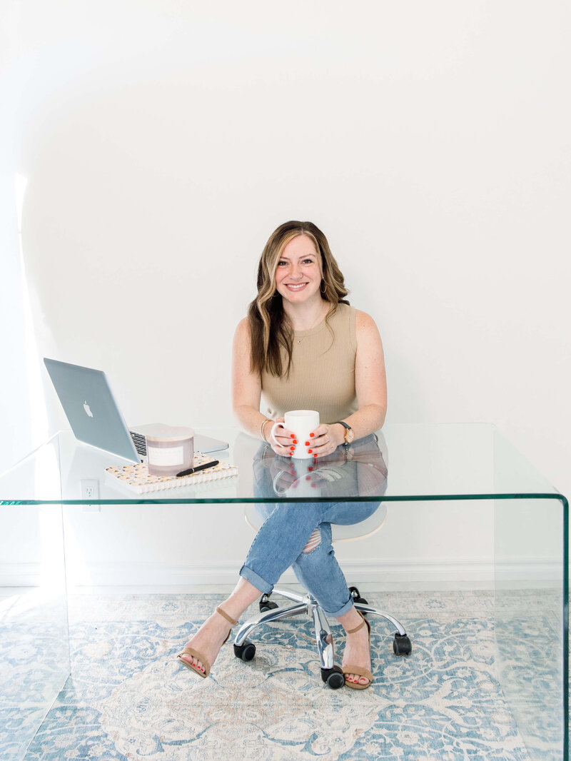 woman at glass desk holding a coffee cup and smiling