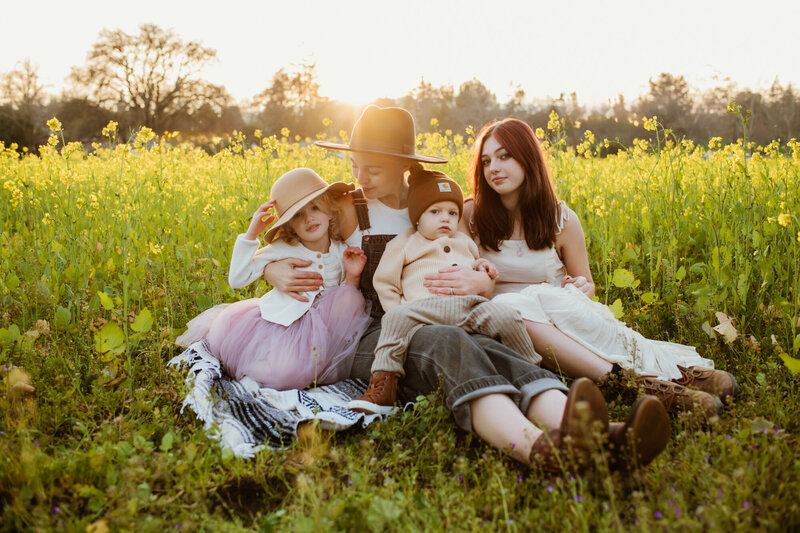 Christina Landini snuggling her two daughters and son during golden hour in a field of golden flowers