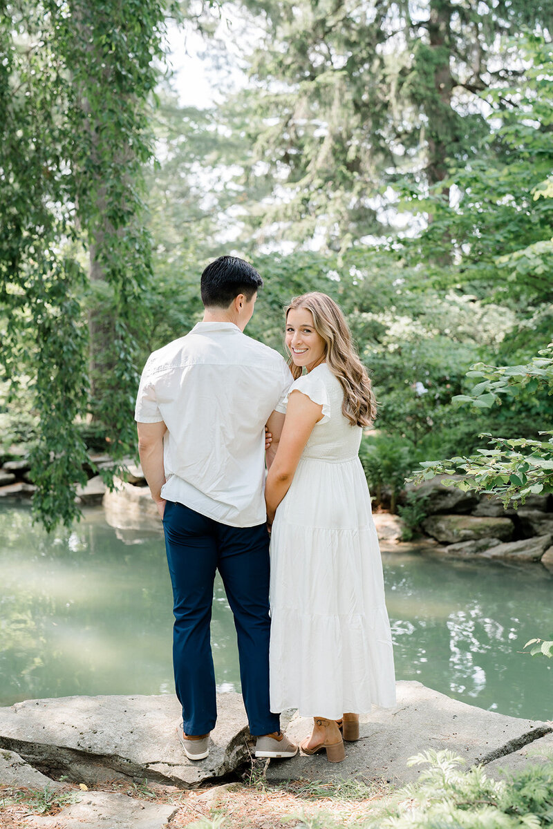 A couple stands embracing by a pond in a garden in New Jersey.