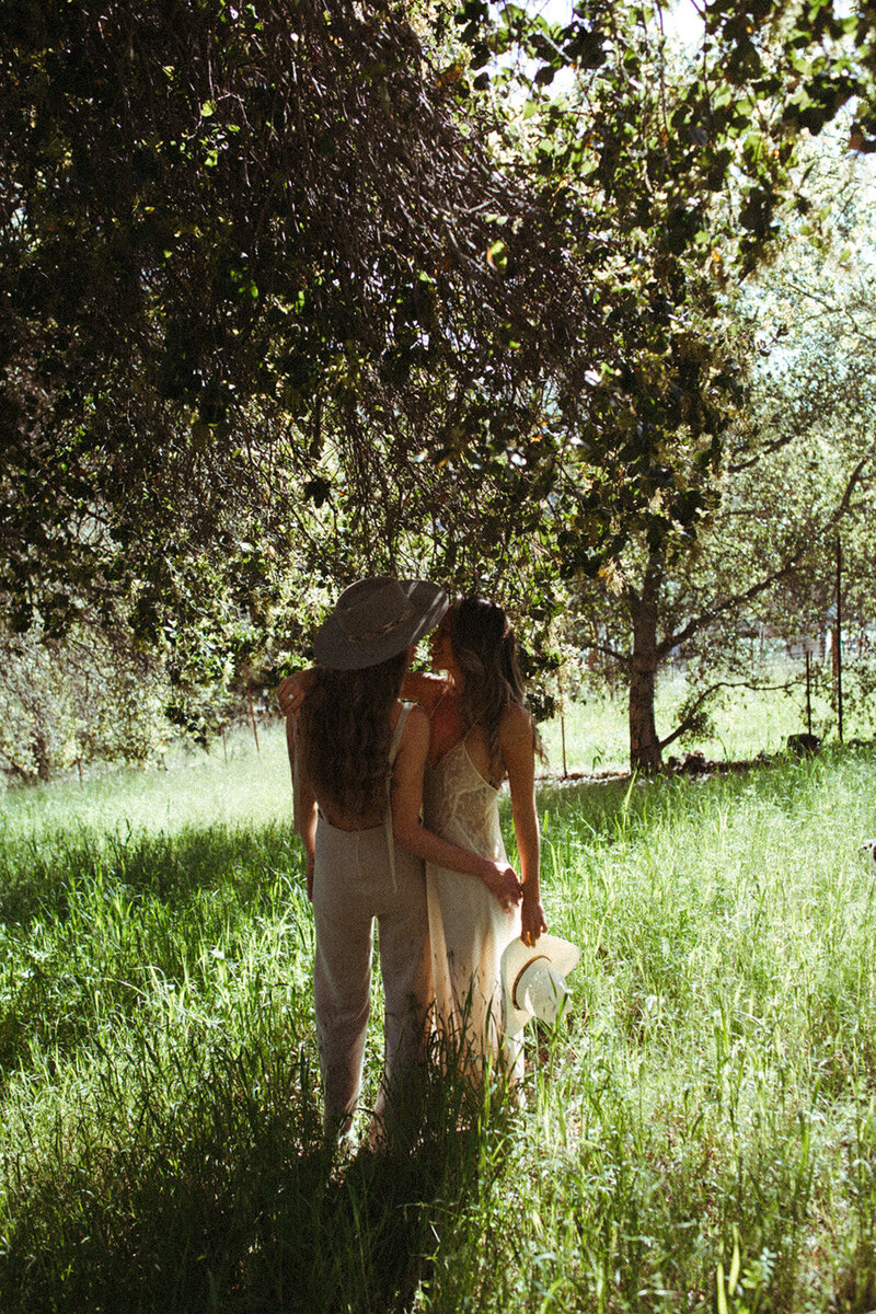A lesbian couple kiss in a field in Sonoma