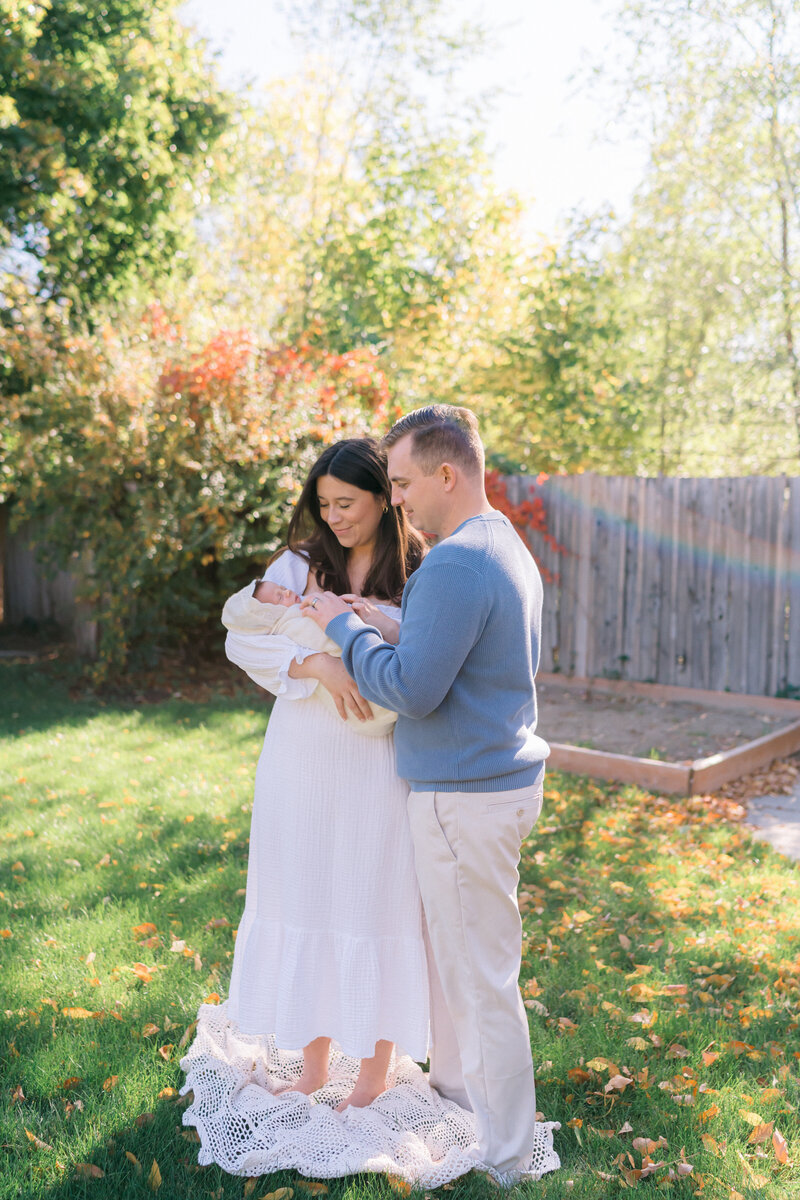 Sunlight newborn session outdoors in home in Sugar House Utah, captured  into the nursery as dad kisses baby boy’s forehead, and walked outdoors to their garden in the city. Captured by newborn photography in Salt Lake City utah 