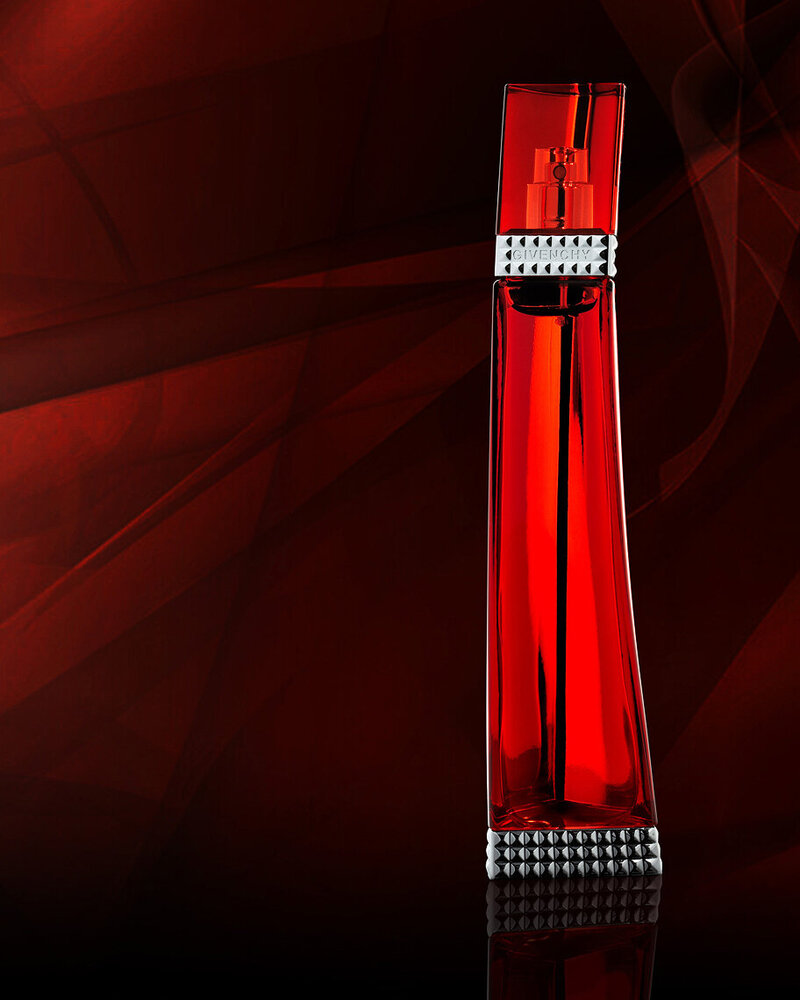 Givenchy perfume bottle in a sleek red design, displayed against a dramatic dark red backdrop, captured by Ylva Erevall.