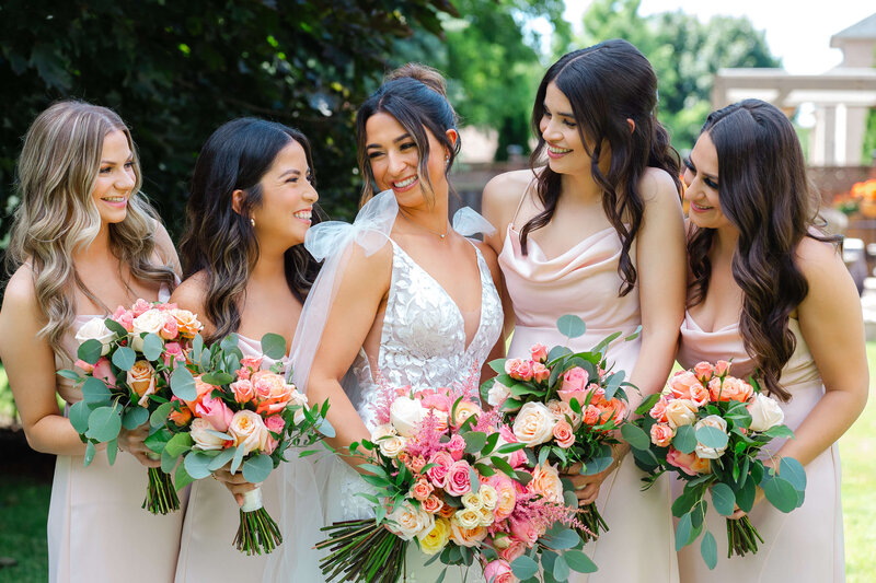 Ottawa wedding photography of a bride and her bridesmaids in pink dresses laughing and smiling