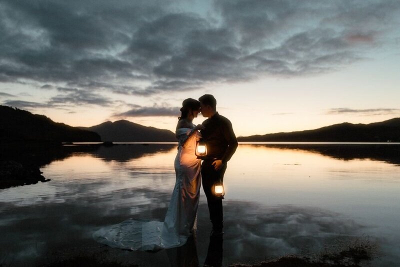 Couple stand in between two mountains and hold each other during sunset in Glencoe, Scotland