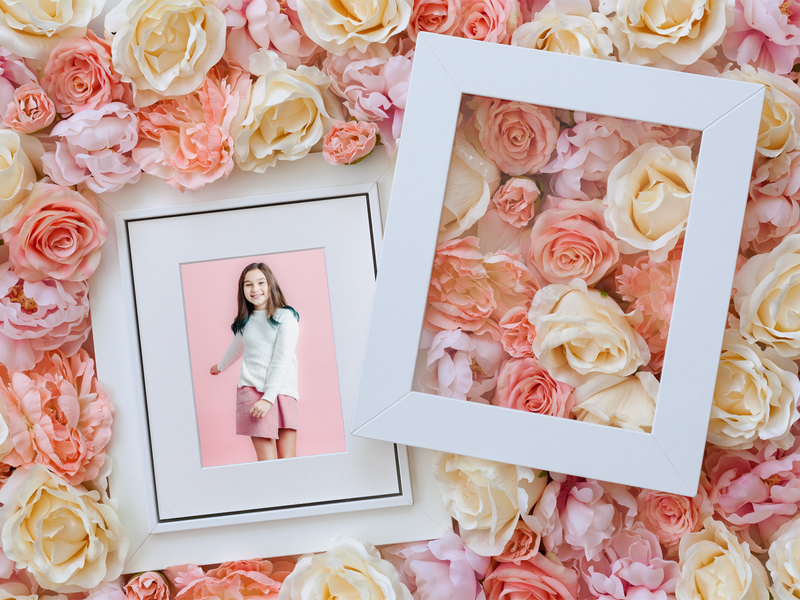 Portrait of a girl in a white frame surrounded by flowers.