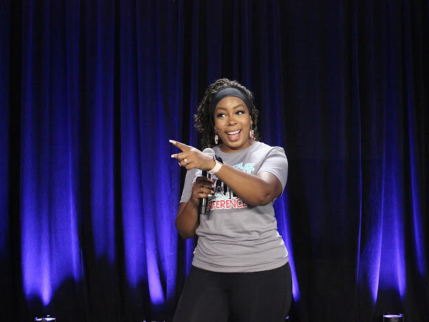 Deonna speaking into a microphone and pointing