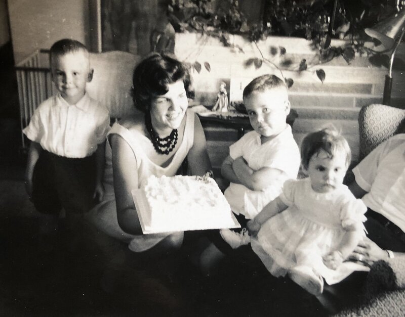 Sybil smiling with her kids while holding a birthday cake