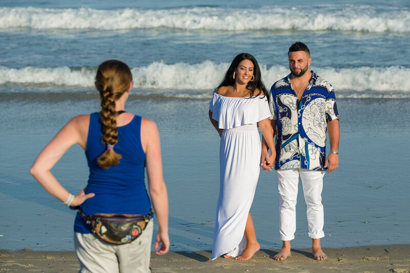 Jen Stitt standing and posing on the beach during an engagement session, demonstrating a flattering pose to an engaged couple, showcasing her expertise in creating stunning beachside engagement photos.