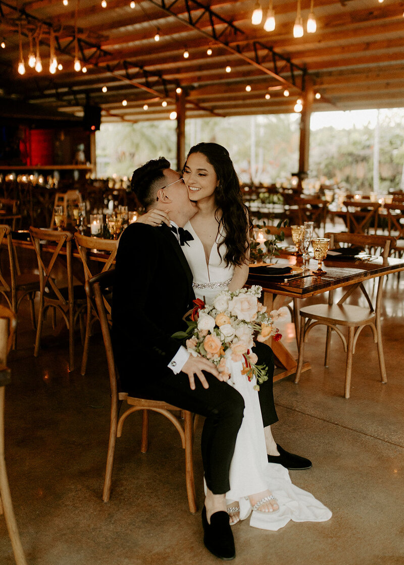 Sebastian laughing into Bianca's neck as she sits on his lap.