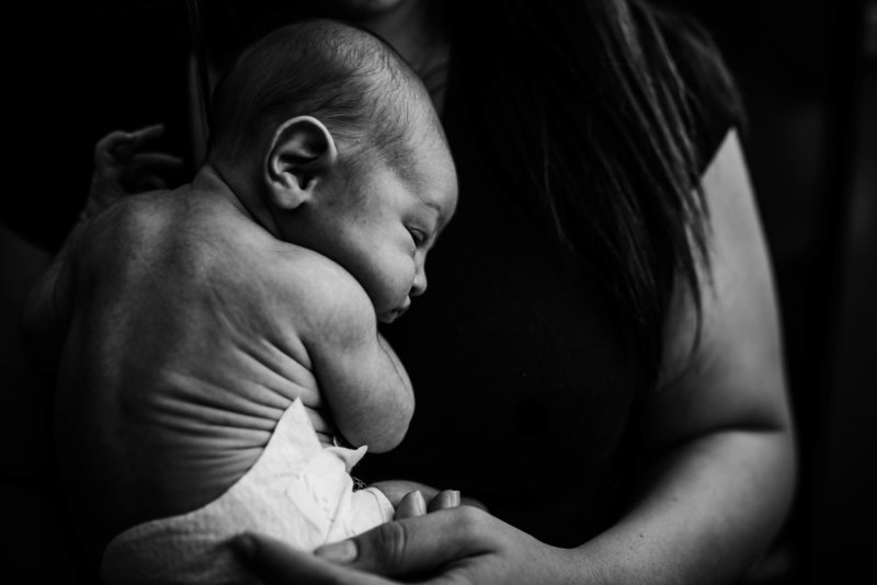 Mom holding newborn during lifestyle photo session in Moose Jaw