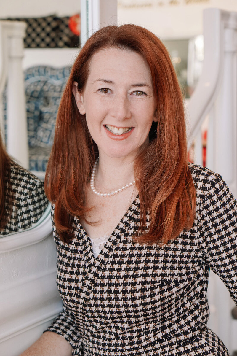 Portrait of photographer, Carolyn Ann Ryan, wearing a checkered dress and pearl necklace.