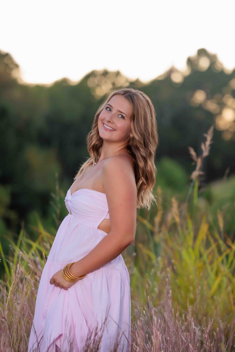 Powerful high school senior portrait at sunset on a Raleigh rooftop wearing pink pants.