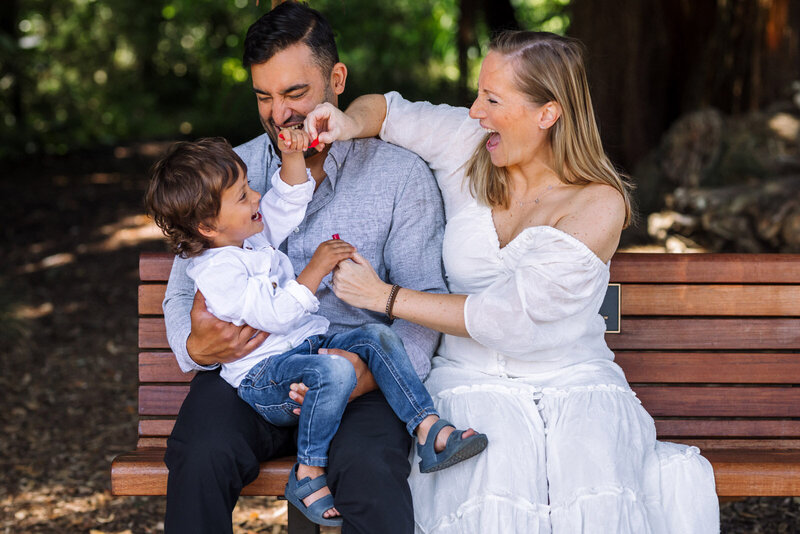family sitting on a bench in a garden laughing and playing with bubbles