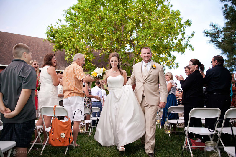 Couple walk down the aisle at ceremony next to Green Farm Barn at Chatfield Farms