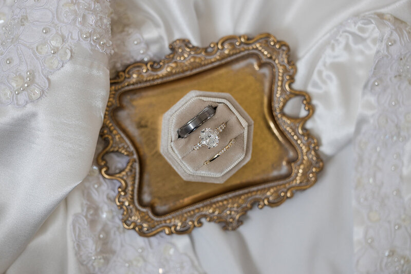 Close-up of diamond engagement ring and wedding band on a soft velvet surface, reflecting natural light.