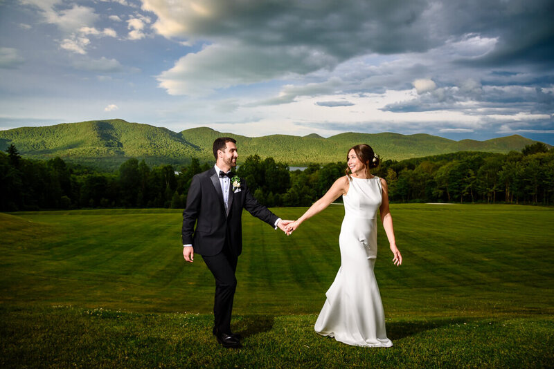 couple holds hands in front of a stunning mountain view during their summer wedding at Mountain Top Resort in Chittenden, Vermont, captured by Eaton Photo
