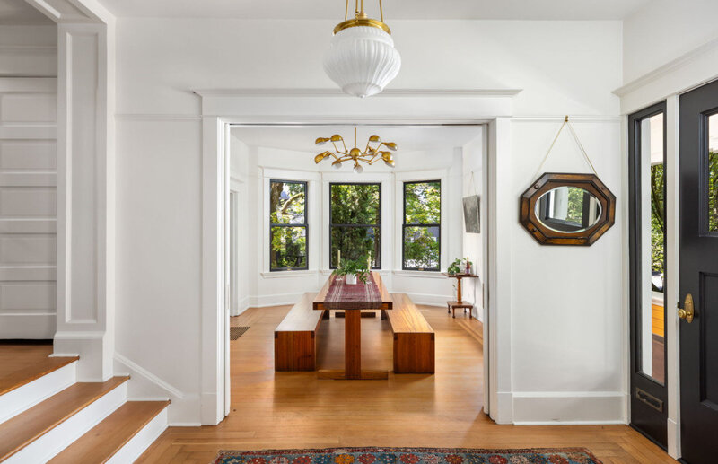 A staged home ready to sell in Portland Oregon features an entryway that looks into a dining room with a modern table.