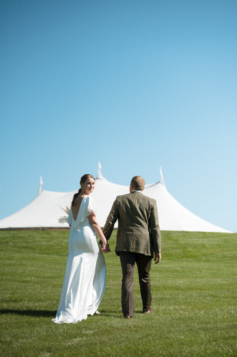 Bride and groom walking towards tent for the reception of their Portland, Maine wedding