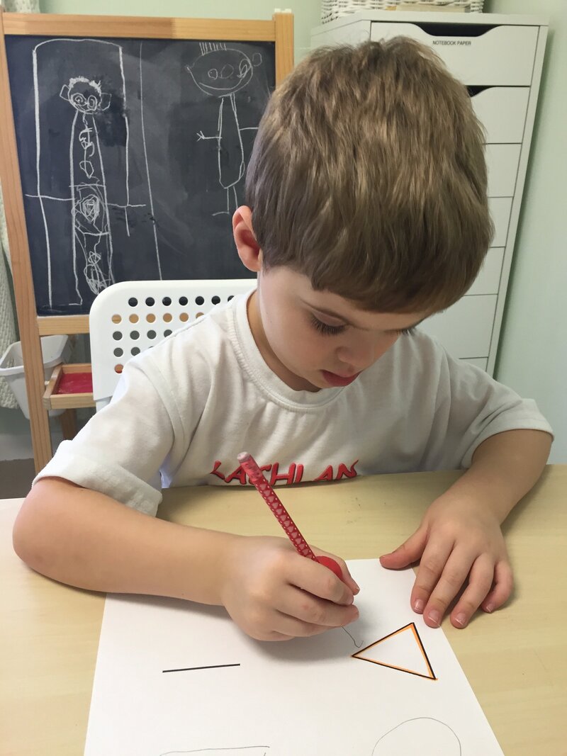young boy sitting at desk writing
