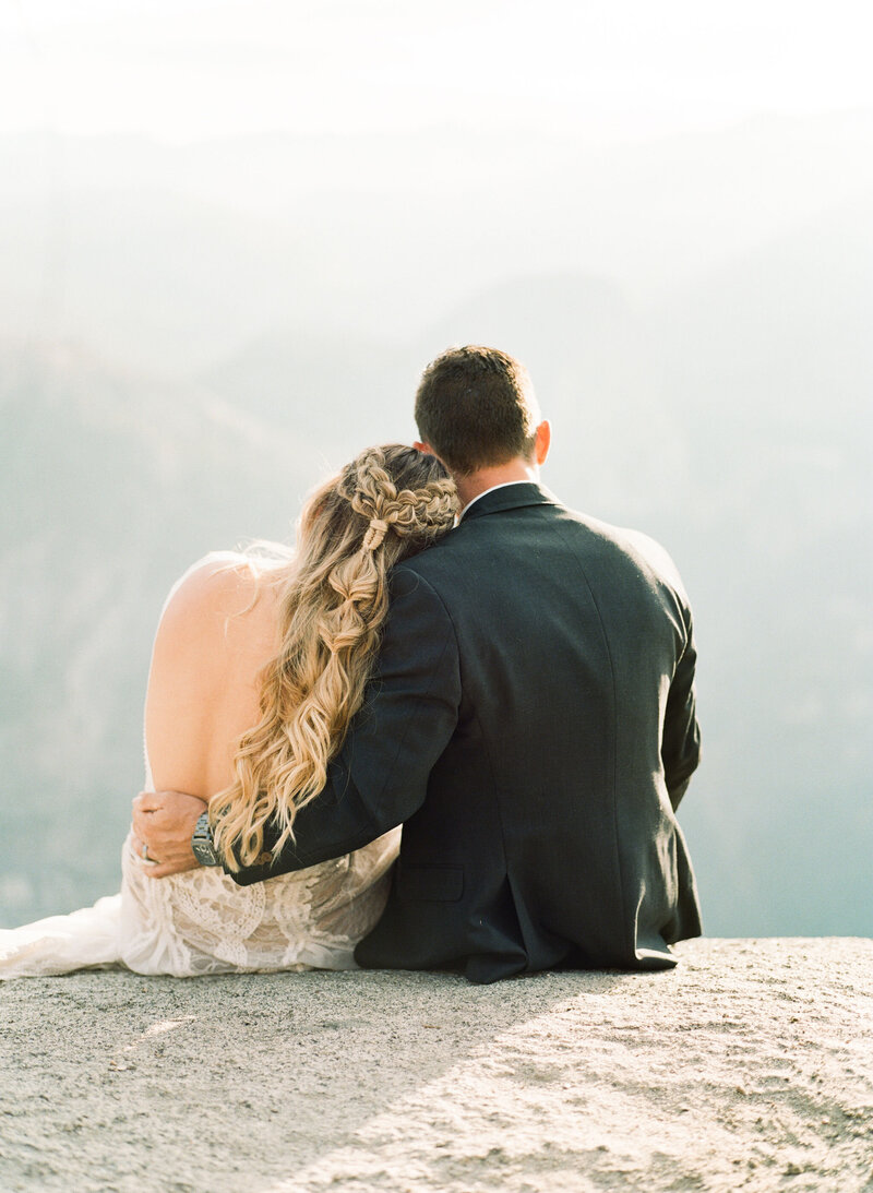 Bride and groom sitting on Yosemite cliff
