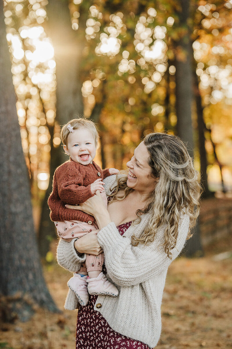 pregnant mom holds toddler daughter on top of bare belly