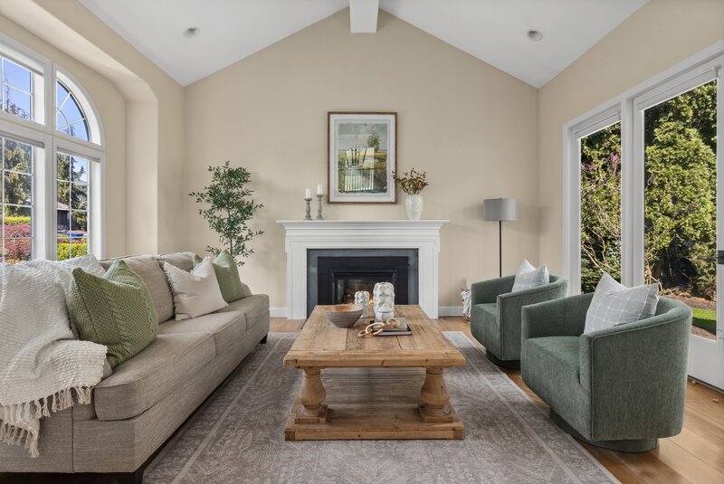 Traditional living room staged by Modern Mollusk in Snohomish County featuring neutral furnishings, green accents, and a cozy fireplace.